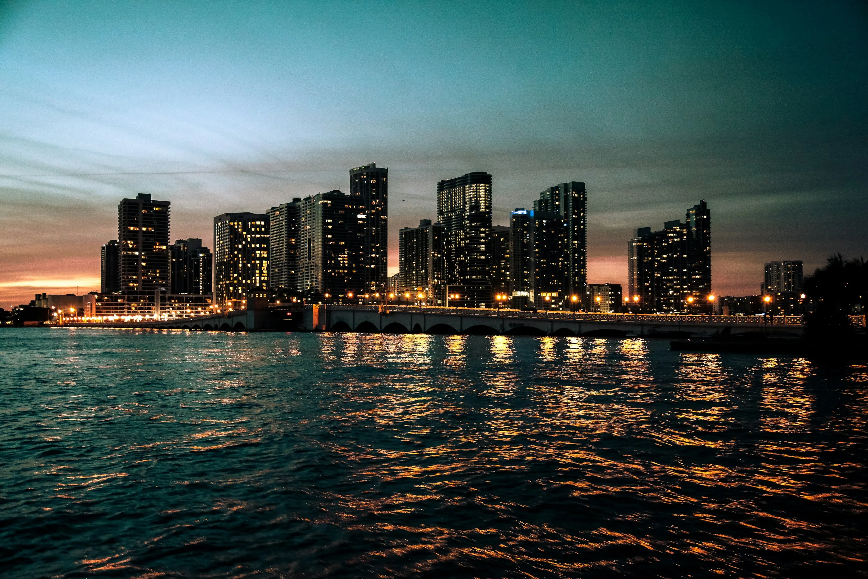 City skyline glowing across the water at dusk